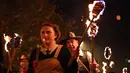 Peserta melakukan pawai sambil membawa obor dalam perayaan Bonfire Night melintasi jalan di Sussex Timur, Inggris, Selasa (5/11/2019). Tak hanya itu, penduduk Inggris juga akan membawa patung berukuran besar dan mengaraknya sembari berparade. (Ben STANSALL/AFP)