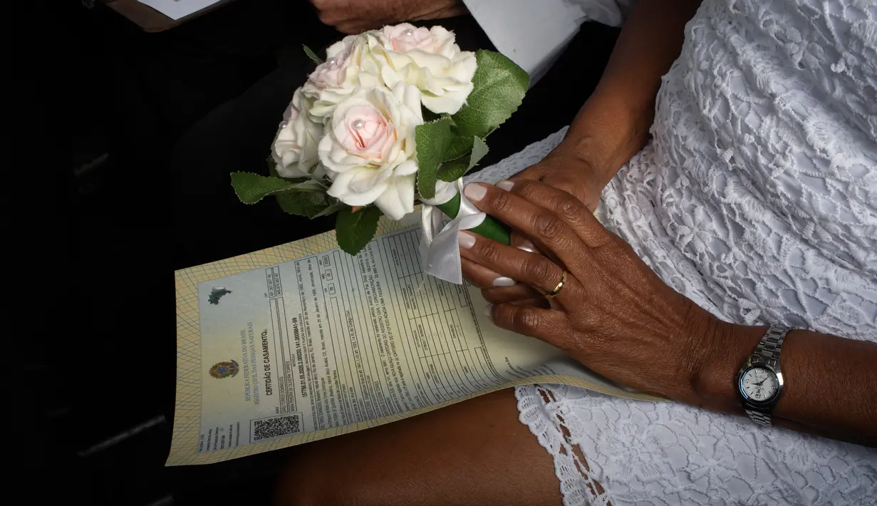 Mempelai wanita memegang buket bunga selama pernikahan drive-thru di kantor pencatatan sipil di Santa Cruz, Rio de Janeiro, Brasil, 28 Mei 2020. Fasilitas ini untuk memudahkan dan membantu pasangan yang ingin mengesahkan hubungan saat pandemi covid-19. (AP/Silvia Izquierdo)