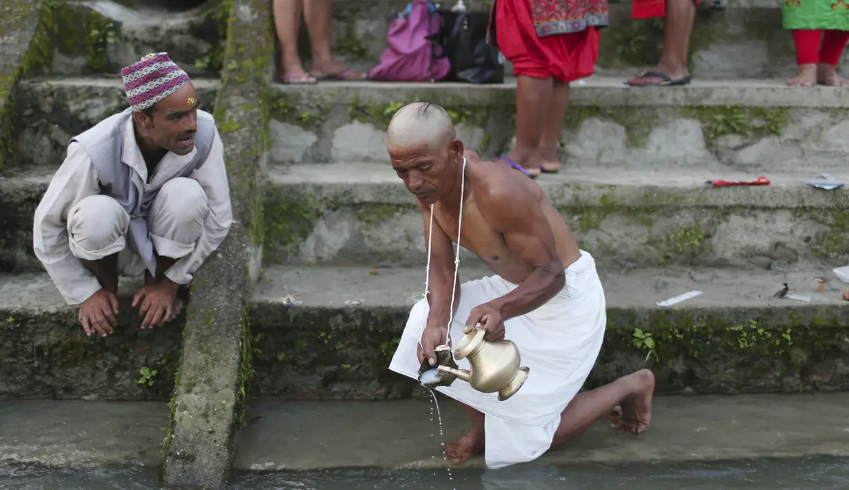 Seorang pendeta Nepal melakukan ritual untuk seorang penyembah selama festival Kuse Aunsi di Kathmandu, (30/8/2019). Kuse Aunsi lebih dikenal dengan sebutan Gokarna Aunsi adalah perayaan yang terjadi pada akhir Agustus, tergantung pada kalender lunar. (AP Photo/Niranjan Shrestha)