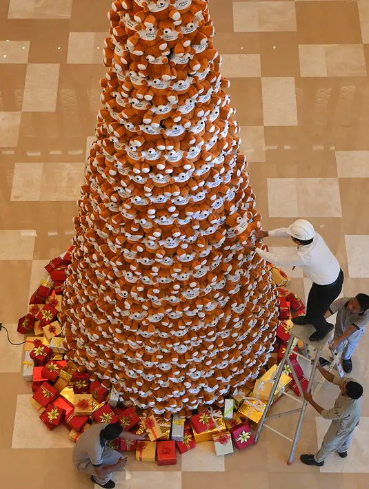 Seorang staff menyusun boneka beruang teddy membentuk pohon Natal di lobi sebuah hotel di Bangalore, India, Rabu (28/11). Ratusan boneka beruang disusun sedemikian rupa hingga membentuk pohon natal cantik. (MANJUNATH KIRAN / AFP)
