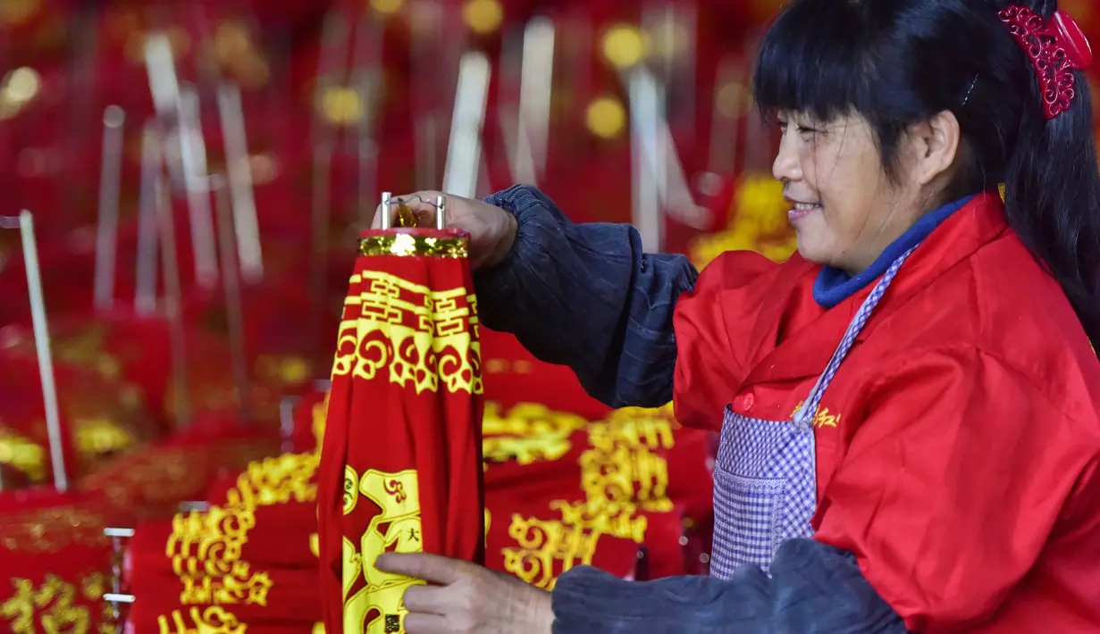 Seorang pekerja membuat lentera merah menjelang perayaan Tahun Baru Imlek 2020 di sebuah pabrik di Wuyi, China, Kamis (26/12/2019). Beberapa keunikan pada tradisi perayaan Imlek yang masih dijalani warga Tionghoa adalah menggantung lentera merah. (Photo by STR / AFP)