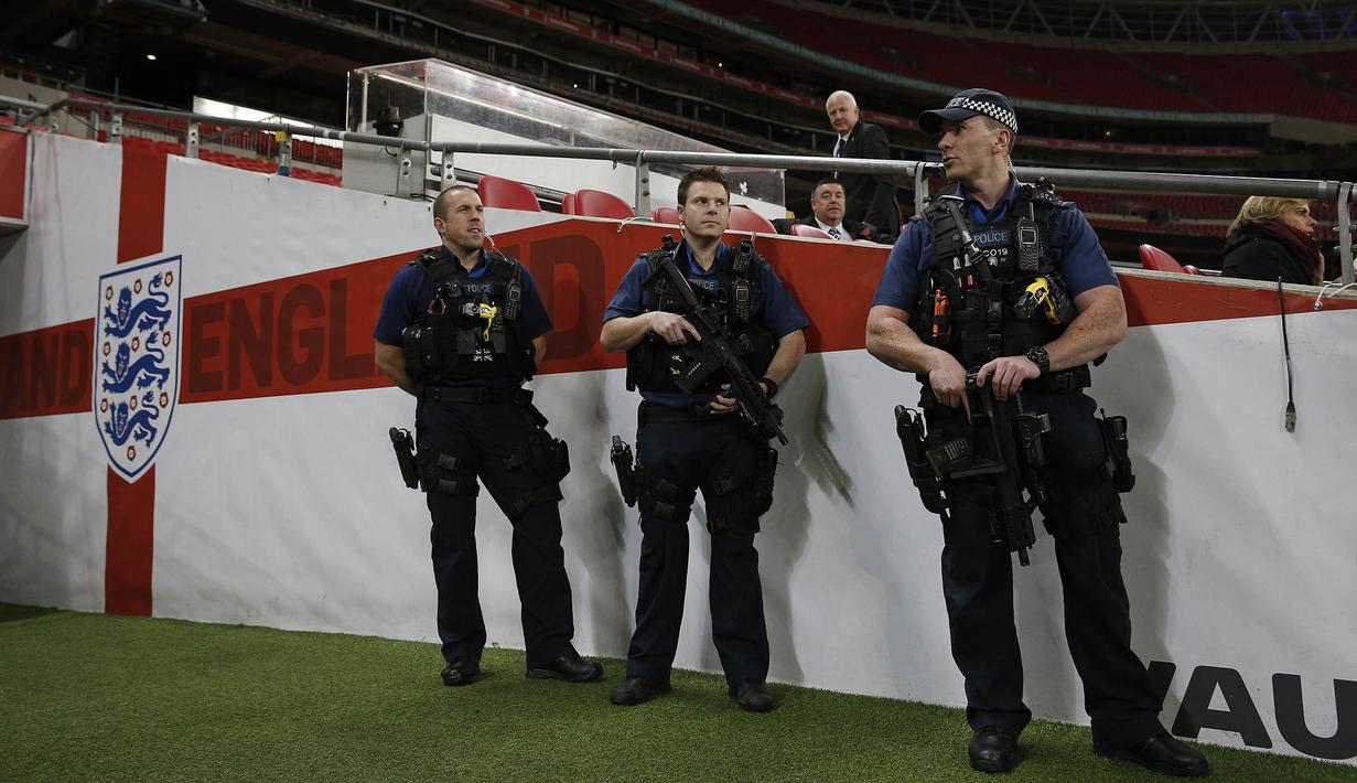 Kepolisian Inggris dengan senjata lengkap menjaga latihan timnas Prancis jelang laga ujicoba melawan Inggris di Stadion Wembley, Inggris, Senin (16/11/2015). (AFP Photo/Adrian Dennis)