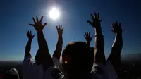 Pengunjung mengangkat tangan mereka untuk menerima energi matahari saat merayakan equinox musim semi di situs arkeologi Teotihuacan, Meksiko (21/3). (AP Photo/Rebecca Blackwell)