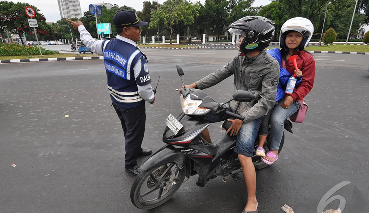 Petugas Dinas Perhubungan DKI Jakarta saat menunjukkan arah kepada seorang pengendara sepeda motor untuk tidak melewati Jl Merdeka Barat,  Jakarta, Kamis (1/1/2015). ( Liputan6.com/Miftahul Hayat)