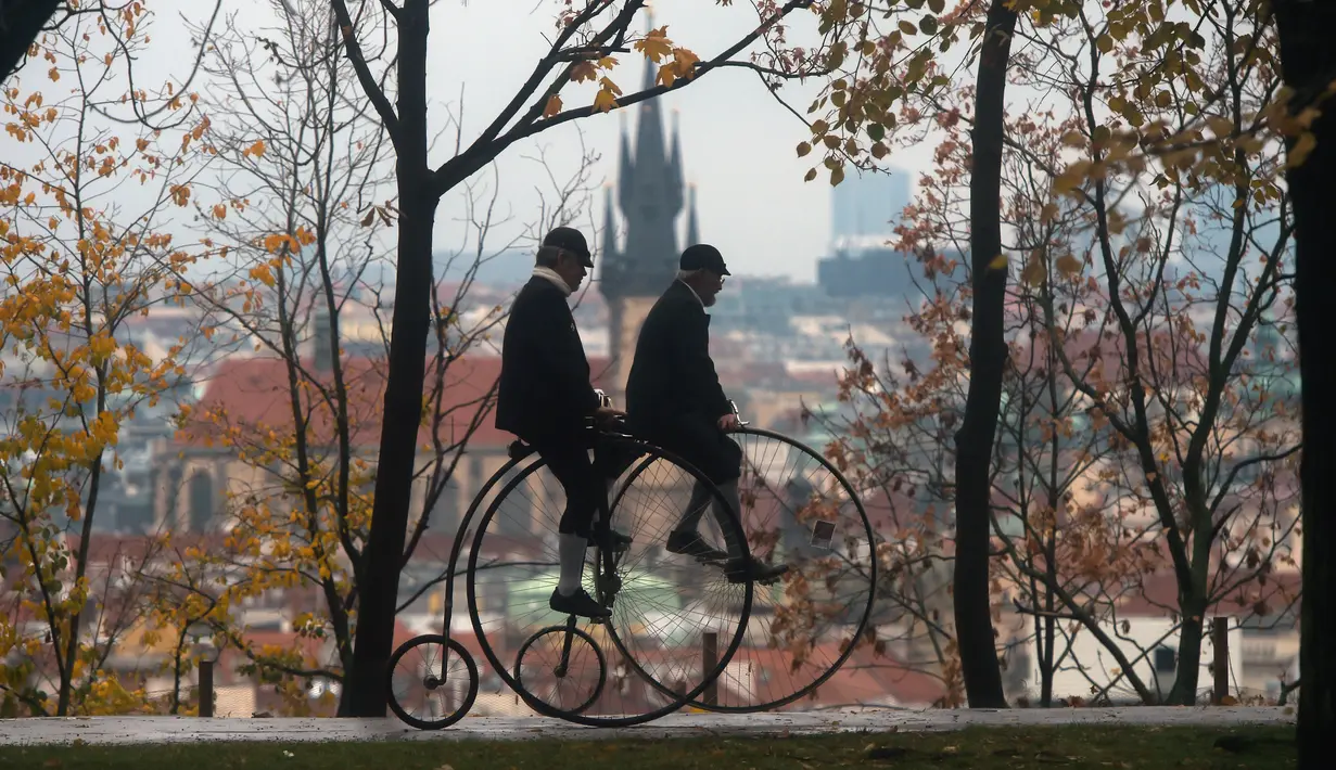 Dua penggemar sepeda mengenakan kostum sejarah sambil mengendarai Penny Farthing atau dikenal sebagai sepeda roda tinggi selama kompetisi tradisonal 'One Mile Race' di Praha, Republik Ceko pada 3 November 2018. (Photo by Michal CIZEK / AFP)