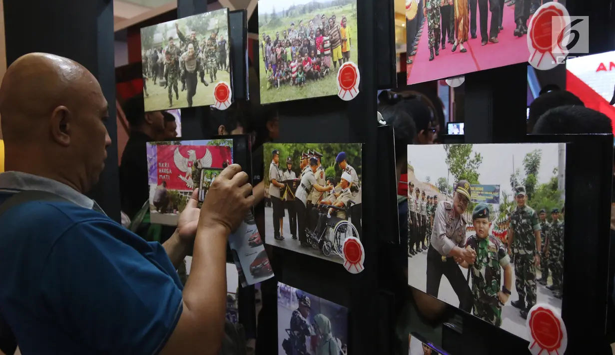 Pengunjung mengambil gambar karya-karya foto pemenang Anugerah Jurnalistik Polri 2018 yang dipamerkan di Gandaria City, Jakarta, Rabu (18/7). Terdapat 641 peserta yang mengikuti lomba melalui karya jurnalistik, foto dan komik. (Liputan6.com/Arya Manggala)