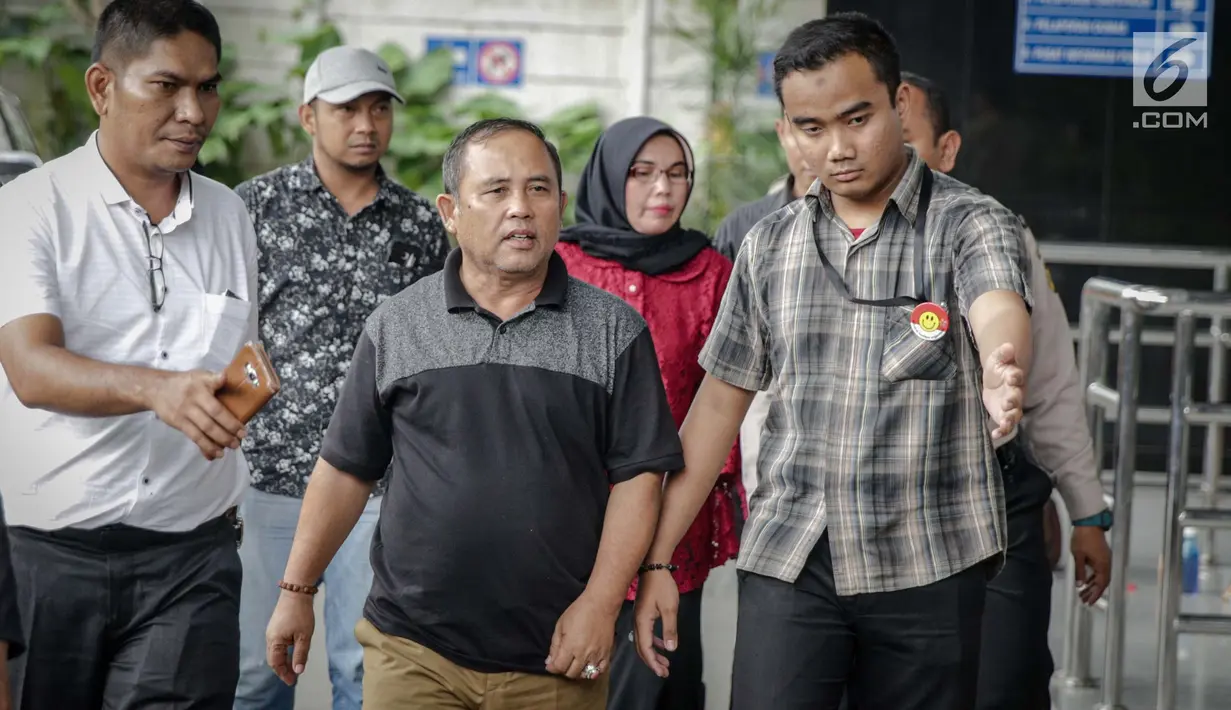 Asisten III Pemprov Jambi Syaifuddin (tengah), Anggota DPRD Jambi Nurhayati (belakang) dikawal petugas memasuki Gedung KPK, Jakarta, Rabu (29/11). KPK melakukan operasi tangkap tangan di Provinsi Jambi. (Liputan6.com/Faizal Fanani)