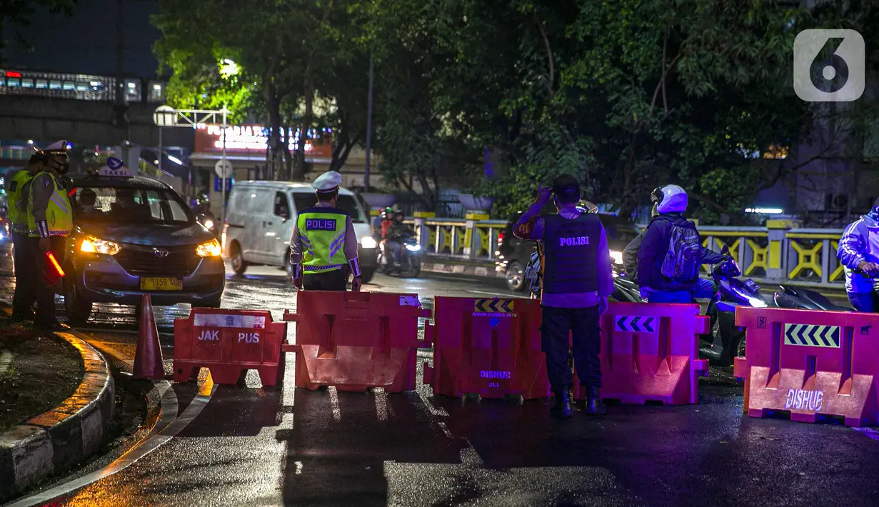 Polisi berjaga saat penyekatan jalan di kawasan Pasar Baru, Jakarta, Kamis (31/12/2020). Polda Metro Jaya menutup sejumlah ruas jalan selama Car Free Night dan Crowd Free Night pada malam Tahun Baru 2021 untuk mencegah penyebaran COVID-19. (Liputan6.com/Faizal Fanani)