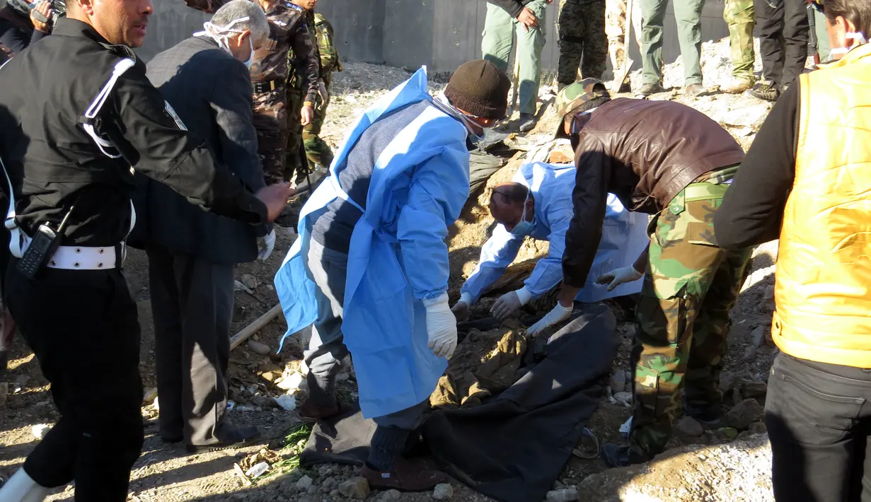 Polisi Irak mengumpulkan jasad yang dieksekusi oleh kelompok ISIS di sebuah kuburan massal  di Kota Ramadi, sebelah barat Baghdad, Selasa (26/1). Kuburan massal tersebut berisi sisa-sisa sekitar 40 jasad. (AFP/ MOADH AL-DULAIMI)