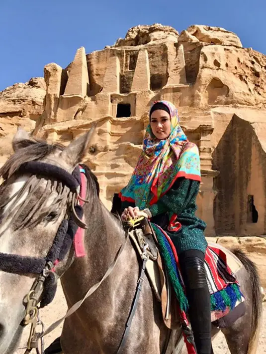 Gaya penyanyi Mulan Jameela saat berpose sambil menunggangi kuda di depan situs bersejarah Petra yang berada di Amman, Yordania. (Instagram/@mulanjameela1)