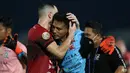 Pemain Bali United, Ilija Spasojevic (kiri) memeluk kiper Madura United, Muhammad Ridho usai mengalami cedera dalam laga pekan ke-16 BRI Liga 1 2021/2022 di Stadion Sultan Agung, Bantul, Kamis (09/12/2021). (Bola.com/Bagaskara Lazuardi)