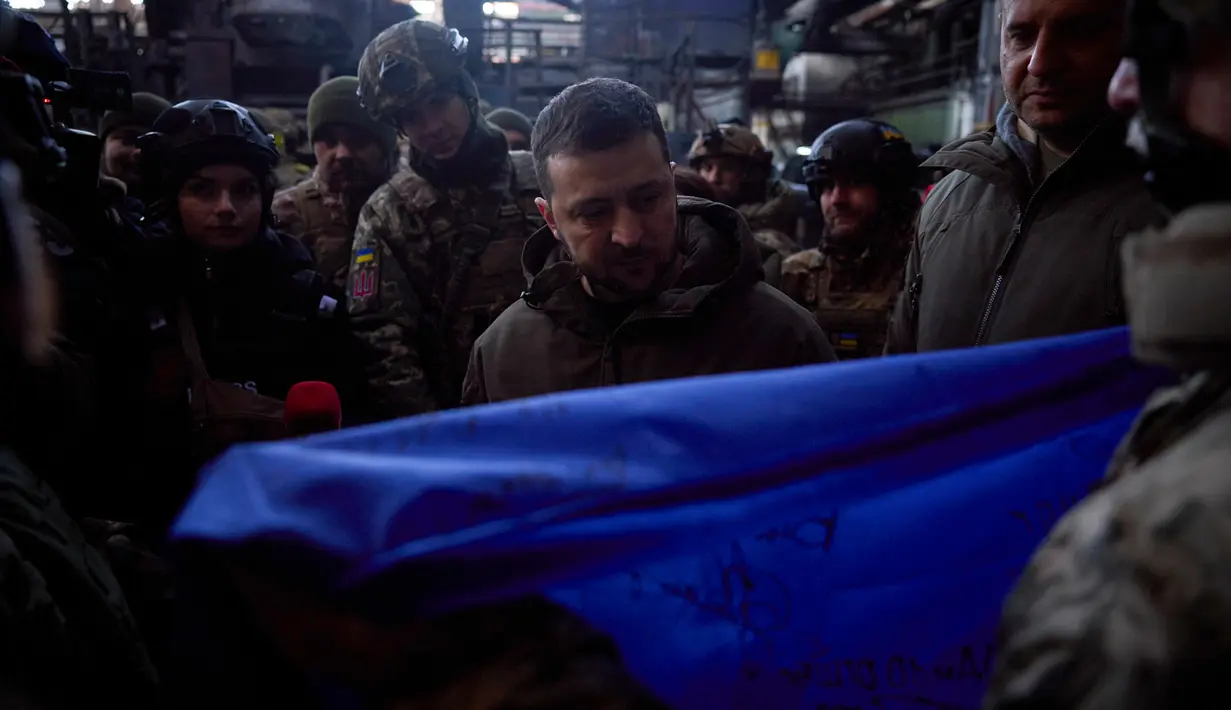 Presiden Ukraina Volodymyr Zelenskyy menandatangani bendera nasional Ukraina di lokasi pertempuran terberat melawan Rusia di Bakhmut, Ukraina, 20 Desember 2022. Zelenskyy mengatakan bahwa upaya Rusia untuk menaklukkan Bakhmut telah mengubah kota itu menjadi reruntuhan. (Ukrainian Presidential Press Office via AP)