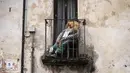 <p>Sebuah gambar yang diambil pada 3 Mei 2022 menunjukkan orang-orangan sawah di balkon selama pekan raya tahunan di desa Castellar, Italia utara, dekat Cuneo. Warga menghias orang-orangan sawah layaknya manusia. Seperti mengenakan gaun, kemeja, topi, dan kaca mata lalu menempatkannya di kebun, halaman, ladang serta jalan.(MARCO BERTORELLO / AFP)</p>