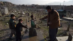 Afghan Zilgai (9) mendapat bayaran setelah menyiram makam kerabat dari seorang peziarah di pemakaman Kart-e-Sakhi, Kabul, 20 Februari 2016. Anak sulung dari 8 bersaudara itu menjual air dari fajar hingga senja kepada para peziarah (AFP PHOTO/Wakil KOHSAR)