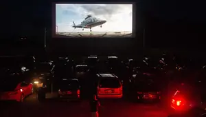 Puluhan mobil terparkir di depan layar bioskop saat pemutaran film drive-in di Family Drive-in di Virginia, 10 Agustus 2018. Menonton film di luar ruangan atau drive-in merupakan bagian penting dalam industri hiburan di Amerika. (AFP PHOTO/Nicholas Kamm)