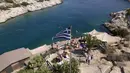Orang-orang berfoto di sebelah bar pantai di pinggiran Vouliagmeni, barat daya Athena, Yunani, Kamis (29/7/2021). Salah satu gelombang panas paling parah yang tercatat sejak 1980-an melanda Eropa tenggara. (AP Photo/Yorgos Karahalis)