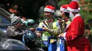 Petugas Kepolisian bersama sinterklas memberikan bunga kepada pengadara sepeda motor di jalan kawasan Tomang, Jakarta, Rabu (23/12). Menyambut Hari Natal 2015, anggota Kepolisian Polres Jakarta Barat kenakan topi Sinterklas. (Liputan6.com/Yoppy Renato)