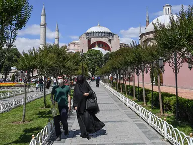 Orang-orang berjalan di depan Hagia Sophia di Istanbul, Turki pada 11 Juli 2020. Hagia Sophia, bangunan berusia 1.500 tahun, saat ini berubah statusnya menjadi masjid. (Ozan KOSE/AFP)