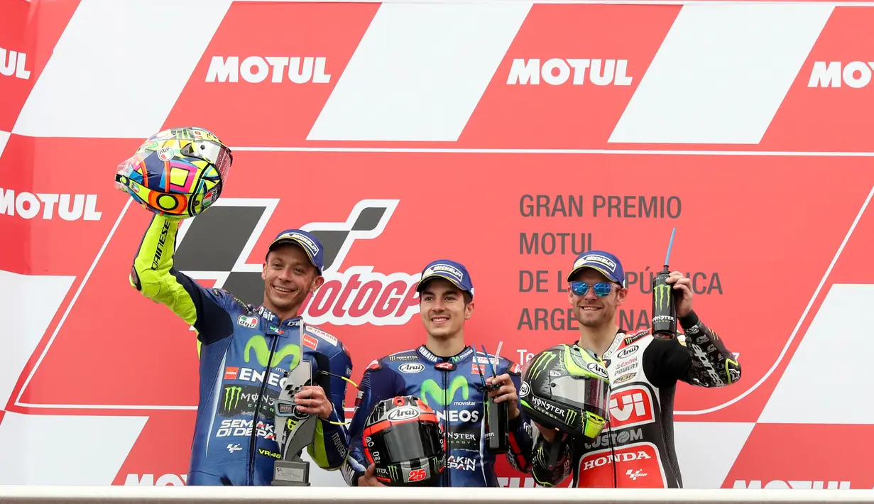 Pembalap Movistar Yamaha, Maverick Vinales sebagai juara MotoGP Argentina, dan rekan setimnya Valentino Rossi serta LCR Honda, Cal Crutchlow memegang trofi mereka di atas podium Sirkuit Termas de Rio Hondo, Minggu (9/4). (AP Photo/Nicolas Aguilera)