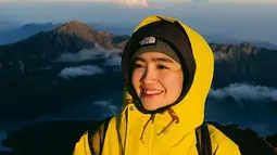 Secerah senyumannya, Febb Rastanty mengenakan jaket kuning saat mendaki Rinjani. (Foto: Instagram/ febbyrastanty)