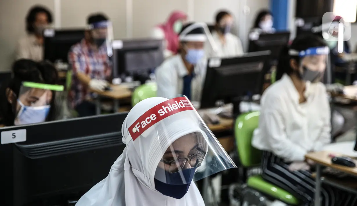 Peserta mengenakan masker dan pelindung wajah saat mengikuti Seleksi Bersama Masuk Perguruan Tinggi Negeri (SBMPTN) di Universitan Negeri Jakarta, Minggu (5/7/2020). Sebanyak 42.463 peserta mengikuti SBMPTN dengan prosedur protokol kesehatan. (Liputan6.com/Faizal Fanani)