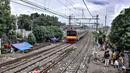 Kereta commuterline melintas di dekat deretan bangunan semipermanen milik tunawisma di kawasan Senen, Jakarta, Minggu (14/2/2021). Aminah (58) sadar tinggal di pinggir rel akan dapat mengancam nyawanya. (merdeka.com/Iqbal S. Nugroho)