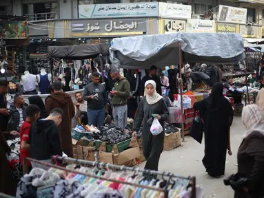 Warga Palestina yang mengungsi berbelanja di kios-kios pasar jalanan sekitar kamp pengungsi Nuseirat, Jalur Gaza tengah, pada Rabu 18 Maret 2026. Meski berada dalam situasi sulit dan di tengah reruntuhan, pasar jalanan sekitar kamp pengungsi Nuseirat, Jalur Gaza tengah, tetap ramai dikunjungi warga Palestina yang mengungsi. (Eyad Baba/AFP)
