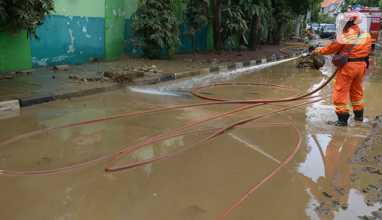 Petugas pemadam kebakaran membersihkan sisa lumpur pascabanjir yang merendam kawasan Bukit Duri, Jakarta, Sabtu (4/1/2020). Meski banjir sudah mulai surut, jalan-jalan dan permukiman warga masih tertutup lumpur tebal. (merdeka.com/Imam Buhori)
