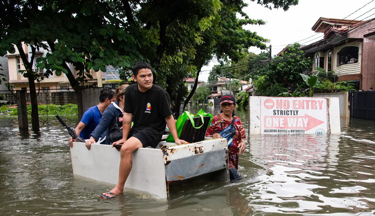 Orang-orang menaiki rakit darurat melewati jalan yang tergenang banjir di sebuah desa di Cainta Town, sebelah timur Manila pada 22 Juli 2025, setelah hujan monsun. (Ted ALJIBE/AFP)