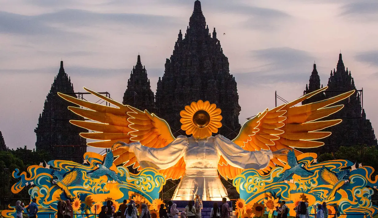 Orang-orang berkumpul di depan "Sunflower Angel", instalasi seni fiberglass setinggi sembilan meter karya seniman lokal Arrofi Ramadhan, di Candi Prambanan, kompleks candi Hindu abad ke-9 yang terdaftar sebagai Situs Warisan Dunia UNESCO, Sleman, Yogyakarta, pada Sabtu 6 Juni 2026. (DEVI RAHMAN/AFP)