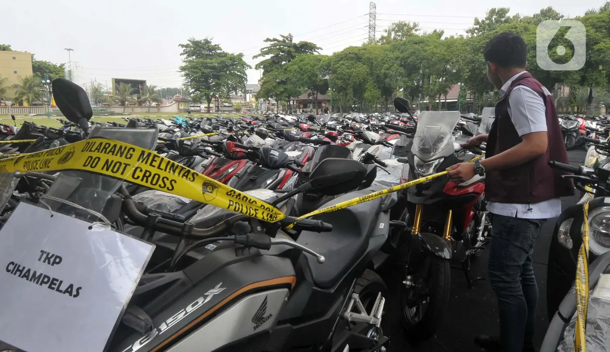 Personel Direktorat Tindak Pidana Umum Bareskrim Polri melakukan pemeriksaan barang bukti pengungkapan kasus tindak pidana fidusia atau penipuan dan penadahan kendaraan bermotor jaringan internasional di Lapangan SLog Polri, Jakarta Timur, Kamis (18/7/2024). (merdeka.com/Imam Buhori)