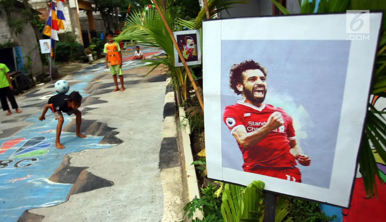 Anak-anak bermain bola di sebuah gang yang dihias  tulisan dan gambar bertemakan Piala Dunia di lingkungan rumahnya di Kinayungan, Pondok Aren, Tangerang Selatan, Kamis (28/6). (Merdeka.com/ Arie Basuki)