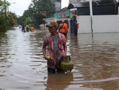 Warga berjalan melewati banjir di Perumahan Ciledug Indah 1 dan 2, Kota Tangerang, Banten, Sabtu (16/7/2022). Banjir tersebut merendam ratusan rumah di dua titik-titik tersebut dengan ketinggian yang bervariasi, mulai dari 50 sentimeter, hingga 1,5 meter. (Liputan6.com/Angga Yuniar)