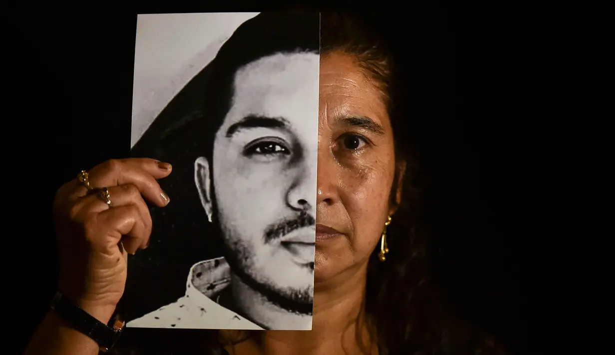 Gladys Betancourth, 51, ibu dari Oscar Obando, 24, satu dari 8 pemuda yang dibunuh dalam pesta di pinggiran Samaniego, Kolombia pada 16 Agustus, berpose dengan foto putranya pada 2 September 2020. Pembunuhan kembali berdarah di pedesaan Kolombia. Korbannya kebanyakan masih muda. (Luis ROBAYO/AFP)