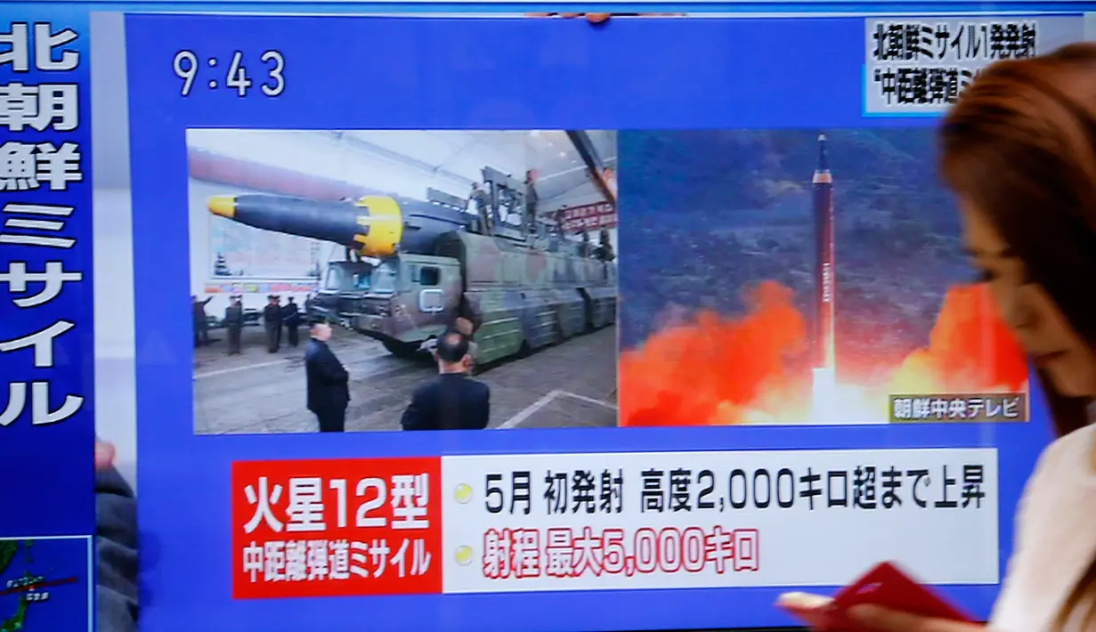 Seorang wanita berjalan melewati sebuah layar TV yang menyiarkan peluncuran rudal Korea Utara di Tokyo, Jepang, Selasa (29/8). Sejak Kim Jong-un berkuasa pada akhir 2011, Korut telah melakukan lebih dari 80 kali uji coba rudal. (AP/Shizuo Kambayashi)