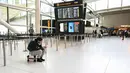 Kondisi ini diberlakukan hingga situasi wilayah udara kembali dinyatakan aman. Tampak dalam foto, seorang penumpang duduk di atas kopernya di bagian kosong area check-in di Bandara Heathrow, London pada Minggu 1 Maret 2026. (JUSTIN TALLIS/AFP)