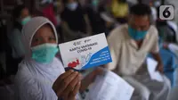 Warga menunjukkan kartu vaksinasi Covid-19 usai mengikuti vaksin di SDN Grogol Utara 09 Pagi, Jakarta, Sabtu (28/8/2021). Vaksinasi yang diikuti 1.000 peserta merupakan kolaborasi yang sejalan dengan semangat RYTHM dari QNet dalam meningkatkan kesehatan masyarakat Indonesia. (Liputan6.com/HO/QNet)