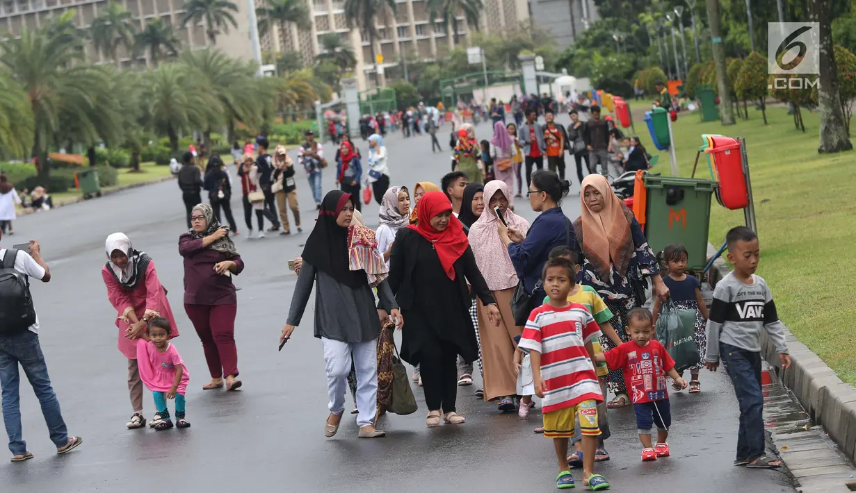 Warga bersama anak-anak berjalan-jalan di kawasan Monumen Nasional, Jakarta, Jumat (19/4). Libur panjang perayaan Paskah 2019 dimanfaatkan warga untuk berwisata di kawasan Monumen Nasional. (Liputan6.com/Helmi Fithriansyah)