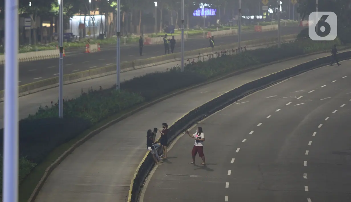 Warga berada di jalan lengang kawasan Sudirman, Jakarta, Rabu (12/5/2021) malam. Polda Metro Jaya memberlakukan crowd free night untuk mencegah kerumunan takbir keliling di malam Idul Fitri 1442 yang berlaku mulai pukul 22:00 malam ini. (Liputan6.com/Herman Zakharia)
