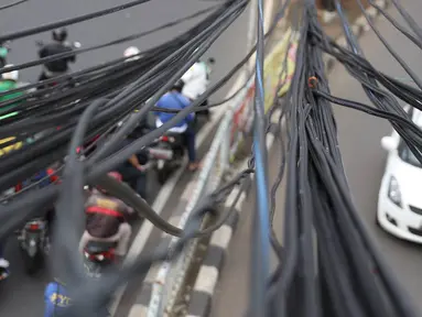 Instalasi kabel semrawut menjuntai di Jalan Dewi Sartika, Jakarta Timur, Sabtu (19/1). Selain mengganggu keindahan kota, kondisi tersebut juga berbahaya karena dapat memicu hubungan pendek arus listrik. (Liputan6.com/Immanuel Antonius)