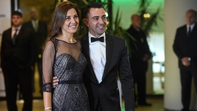 Xavi Hernandez bersama istrinya berpose di karpet merah saat menghadiri pernikahan Lionel Messi di Rosario, Argentina (30/6). Pernikahan Lionel Messi ini dihadiri 260 tamu VVIP. (AFP Photo/Eitan Abramovich)