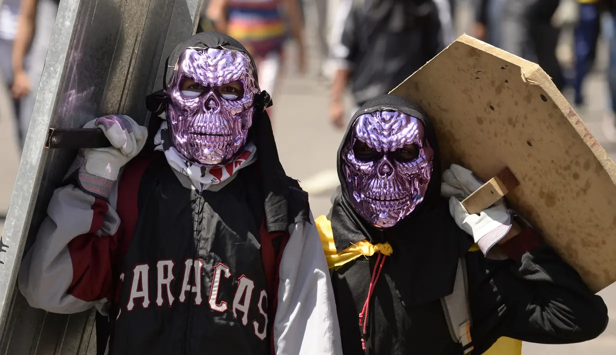 Dua demonstran menggunakan penutup wajah unik saat bentrok dengan polisi antihuru-hara menuntut Presiden Venezuela, Nicolas Maduro, di Caracas (6/7). (AP Photo / Federico Parra)