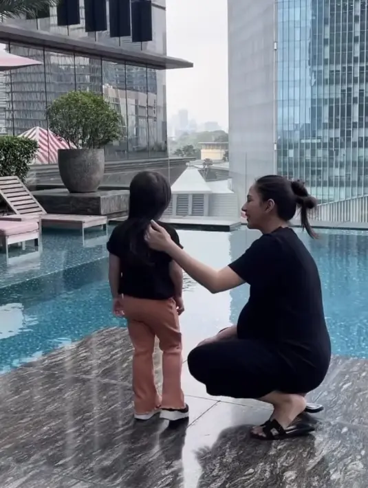 Saat di kolam renang, Jessica Mila mengenakan dress hitam panjang dipadukan sandal Hermes warna serasi. Rambutnya pun diikat ke belakang asal-asalan.  [@asmirandah89]