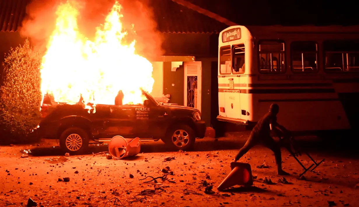 Pengunjuk rasa melemparkan benda ke bus di sebelah mobil polisi yang terbakar selama demonstrasi di luar rumah presiden Sri Lanka di Kolombo (31/3/2022). Tidak dijualnya Diesel melumpuhkan transportasi yang terkena dampak mengalami pemadaman listrik yang sangat lama. (AFP/Ishara S. Kodikara)