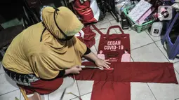 Siti Zahro (44) menggaris pola saat menyelesaikan pembuatan celemek dari tas bansos Covid-19 di industri jahit rumahan KG-Lupe Fashion, Salemba, Jakarta, Senin (16/11/2020). Dalam sehari Siti mampu memproduksi tiga buah celemek. (merdeka.com/Iqbal S. Nugroho)