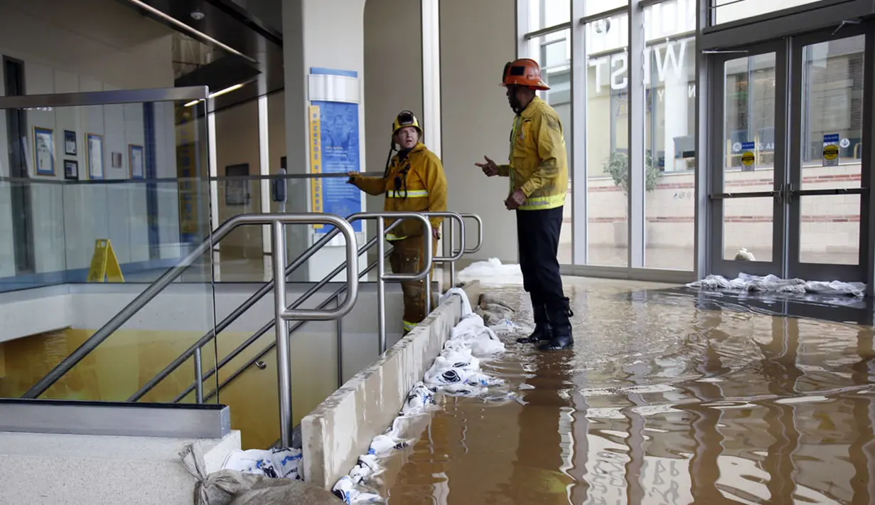 Untuk mencegah air masuk dan menggenangi arena olahraga Pauley Pavilion UCLA, petugas pemadam kebakaran terpaksa membuat bendungan di tangga masuk, (29/7/2014). (REUTERS/Danny Moloshok)