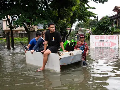 Orang-orang menaiki rakit darurat melewati jalan yang tergenang banjir di sebuah desa di Cainta Town, sebelah timur Manila pada 22 Juli 2025, setelah hujan monsun. (Ted ALJIBE/AFP)