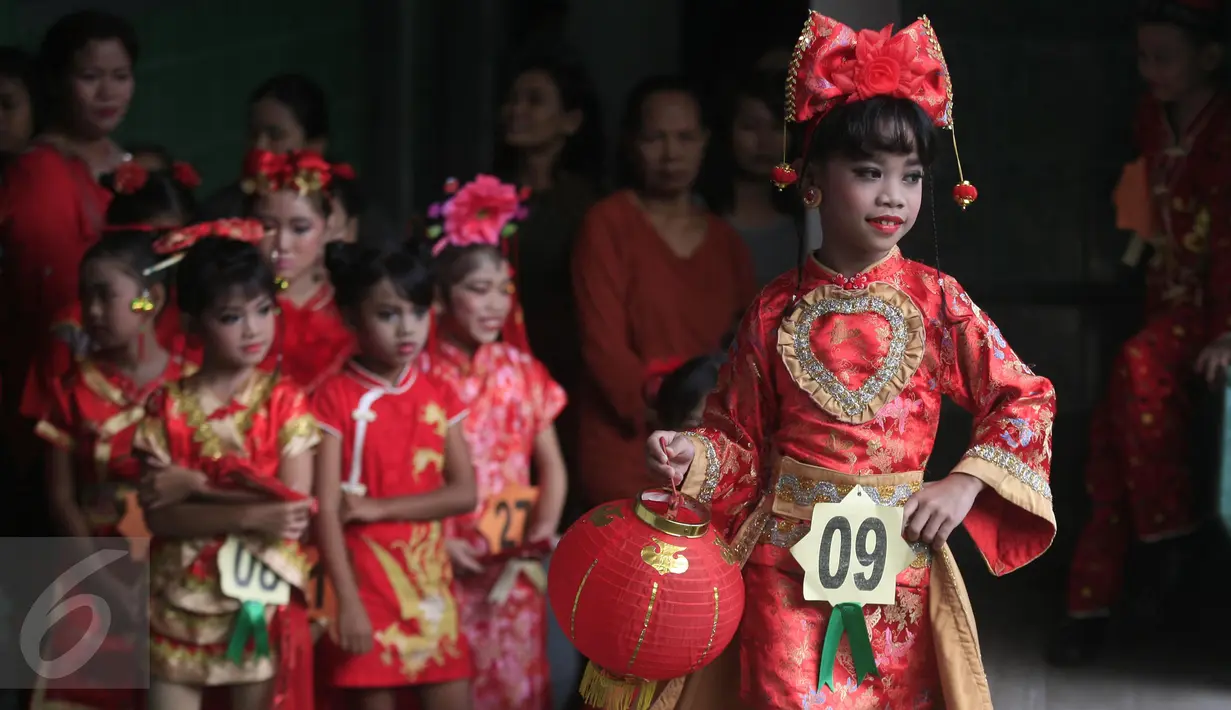 Seorang peserta mengenakan busana cheongsam sambil membawa lampion saat mengikuti fashion show di SD Warga, Solo, Jawa Tengah, Jumat (5/2/2016). Fashion show bernuansa tionghoa diselenggarakan untuk menyambut Tahun Baru Imlek. (Foto: Boy Harjanto)