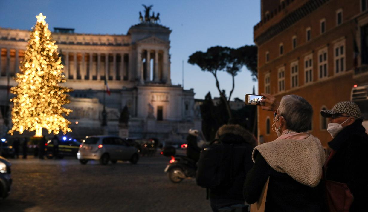 Orang-orang yang memakai masker mengunjungi pohon Natal di Piazza Venezia di Roma, Italia (14/12/2020). Berbagai pernak-pernik dan aksesoris menghiasi kota Roma menyambut Natal. (Xinhua/Cheng Tingting)
