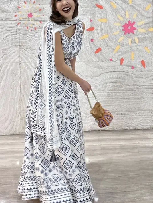 Gisella tampil dengan dress putih bermotif hitam yang serasi dengan selendangnya. [@gisel_la]